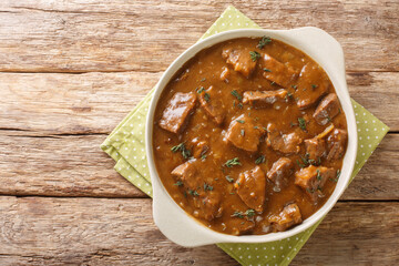 Belgian Carbonnade Beef and Beer Stew closeup in the pot on the wooden table. Horizontal top view from above