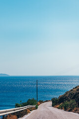 Fototapeta na wymiar Winding roads of Tinos Island with crystal clear water of the Aegean Sea on Tinos island, Cyclades, Greece