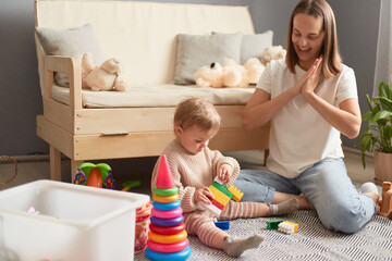 Mother and daughter playing with colorful blocks on the floor of the living room at home....