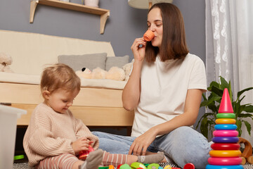 Happy mother and toddler daughter playing games with toys together in comfortable cozy house,...
