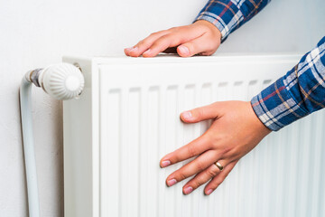Hands on the radiator of the heating system, selective focus. Background