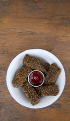 Vegan cuisine. Top view of vegan mozzarella sticks and quinoa with sweet chili dipping sauce in a white bowl on the wooden table.