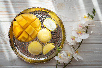 Tasty dessert Mochi with mango fruit on wooden background, close up. Traditional Japanese rice cake dessert