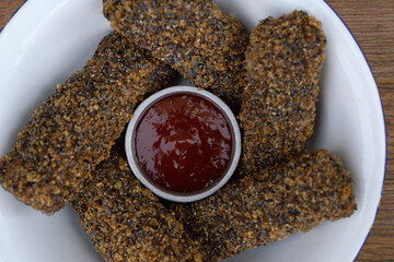 Vegan cuisine. Top closeup view of vegan mozzarella sticks and quinoa with a sweet chili dipping sauce in a white bowl.