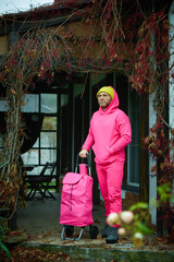 Pink man posing outdoor in pink sport suit with rolling bag. Pink suit