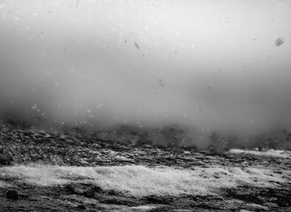 Blurred snow with Focus stacked ground level view of ice accumulation on a sidewalk with blowing snow. 