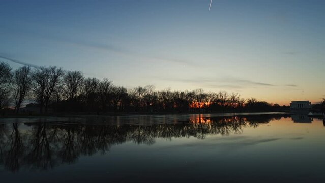 The Lincoln Memorial and reflecting pool in Washington D.C. are captured in this beautiful stock footage clip as the sun sets on the winter solstice. The camera pans from left to right