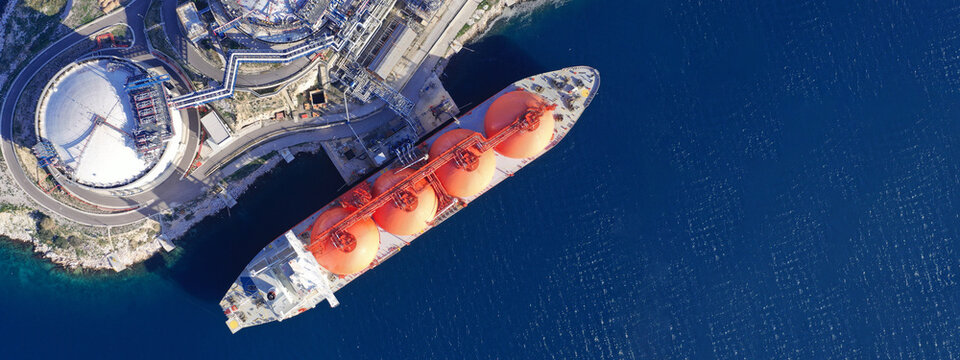 Aerial drone ultra wide photo of LNG (Liquified Natural Gas) tanker anchored in small LNG industrial islet of Revithoussa equipped with tanks for storage, Salamina, Greece