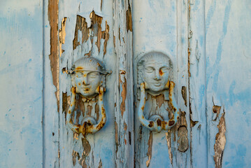 old metal historical doorknob , door with female head figure