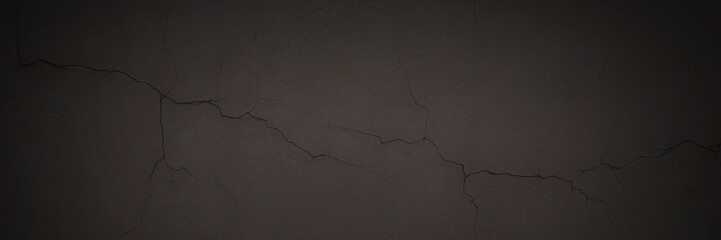 Obraz premium Texture of the old wall. Rough grungy surface of painted plastered concrete wall with spots, cracks, noise and grain. Dark wide panoramic background for design. Shaded vintage texture with vignette.