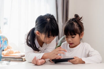 Concept kids and gadgets. Two little girls siblings sisters look at the phone and smile. They hold...