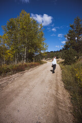 Woman walking on a dirt road holding a basket wearing a white sweater in Boulder county, Colorado - Colorado Rocky Mountain fall winter travel