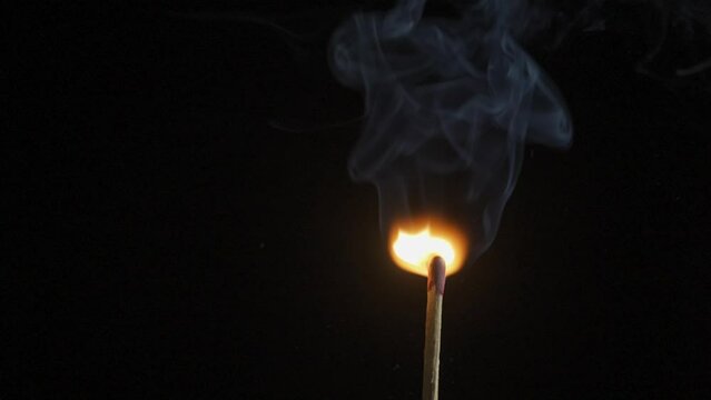 burning wooden match on black background slow motion
