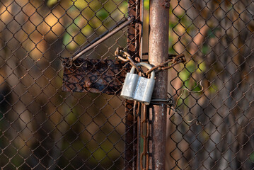 lock on an old rusty mesh gate, chain link fence