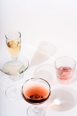 Pattern of glasses for wine and various drinks with daylight and dark shadows on a pink background. The concept of wine tasting, assorted glasses with different drinks.