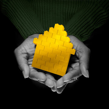 Close-up of Woman's Hands holding Yellow Brick House, Studio Shot