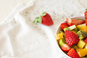 Bowl of healthy fresh fruit salad on white background. Top view