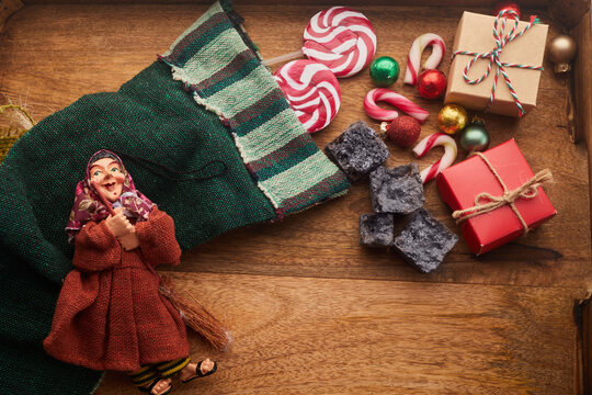 The Befana with sweet coal and candy on wooden background. Italian Epiphany day tradition.