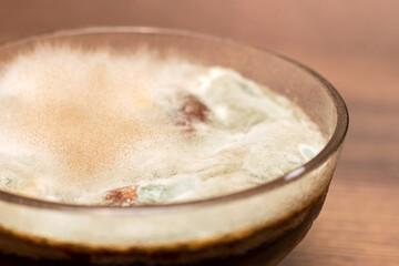 Mold on jam in a glass plate. Moldy food in the plate