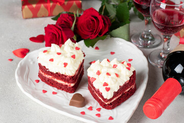 Cakes Red velvet in the shape of hearts on white plate, roses and wine for Valentines Day