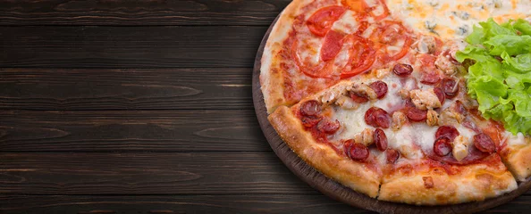Foto op Canvas Assorted pizza, cheese, sausage, meat and tomatoes, on a wooden board © pobaralia