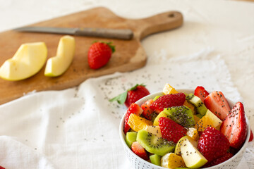 Bowl of healthy fresh fruit salad on white background. Top view
