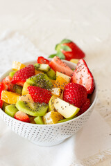 Bowl of healthy fresh fruit salad on white background. Top view