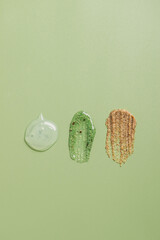 Smears samples of various cosmetics on a pastel green background, copy space. Cosmetic texture