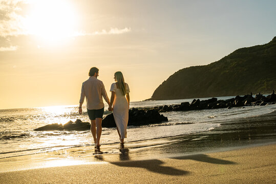 Picturesque romantic couple walking on an empty tropical beach during the sunset on a remote island