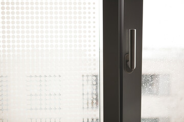 Stylish chrome handle on a dark window frame.