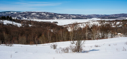 Winter landscape by the frozen lake with hills in the background background. Frozen Lake on a cold winter day