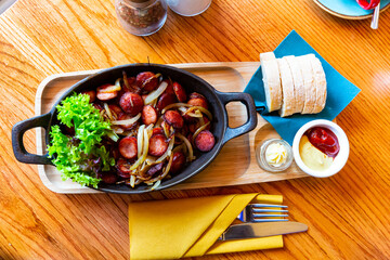 Fried sausages with onions served with butter, sauces and greens, typical Polish cuisine