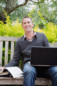 University Student Sitting on a Bench Using a Laptop Computer