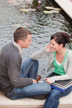 University Students Sitting Together by a Pond