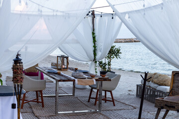 Installation extérieure avec des rideaux blancs et une table et des chaises pour une expérience de diner romantique