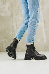 Female legs in jeans and black leather boots. Women's winter shoes