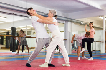 Fototapeta na wymiar Sportive woman conducts painful reception on the eyes of man in the gym. Self defense lessons