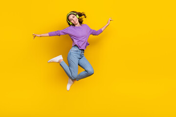 Obraz na płótnie Canvas Full body photo of excited carefree lady jumping listen music empty space isolated on yellow color background