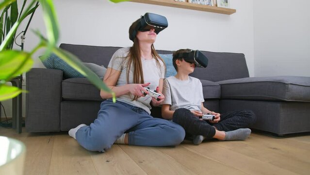 Caucasian mother and son enjoy playing video games together, using gamepads and virtual reality goggles, handheld shot. Digital technology, family time and modern lifestyle concept.