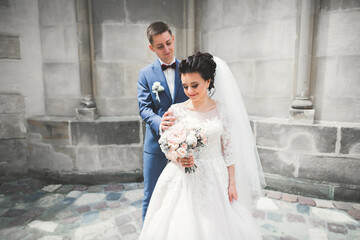 Lovely happy wedding couple, bride with long white dress posing in beautiful city