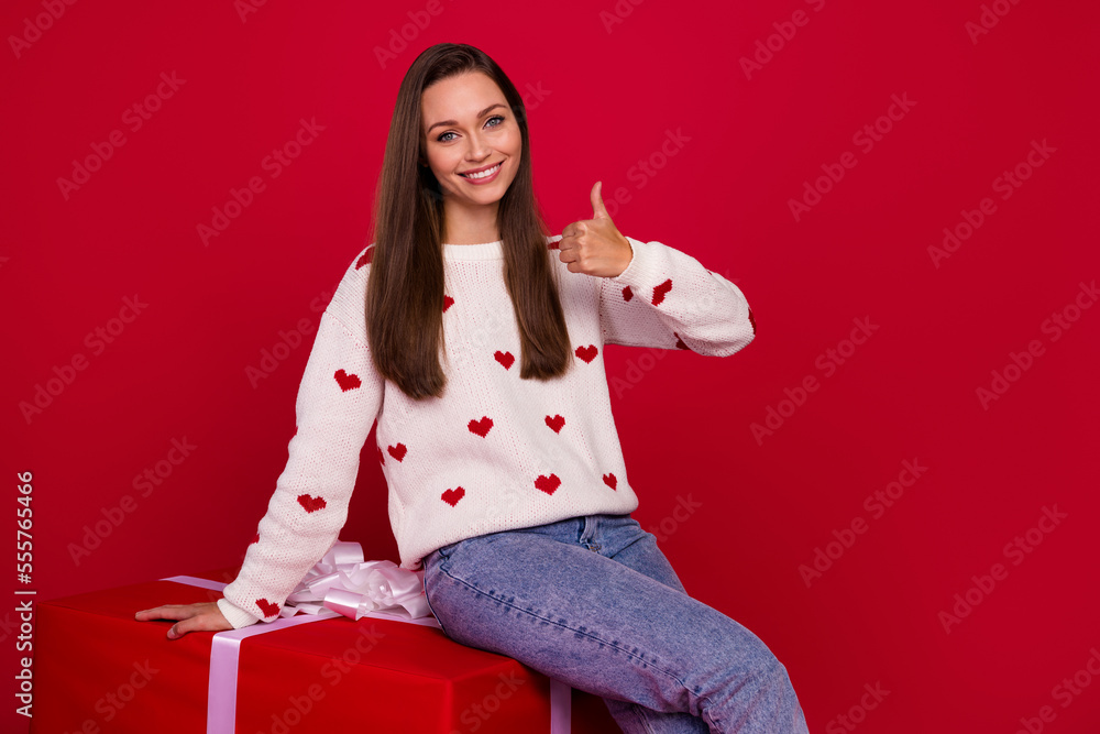 Sticker photo of cute confident girl dressed white pullover showing thumb up sitting gift package isolated r