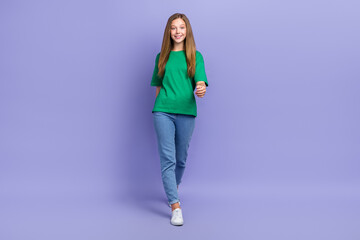 Full length photo of charming adorable small lady wear green t-shirt smiling walking isolated violet color background