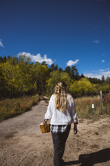 Woman taking pictures on a dirt road looking at fall foliage wearing a white sweater with her back to the camera - Rocky Mountains, Colorado