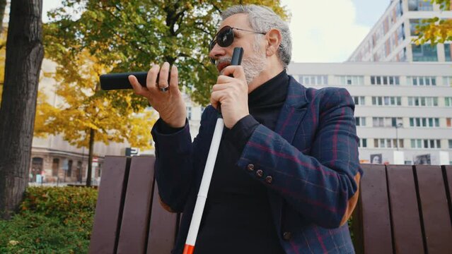 Vision impaired person talking over a smartphone ina an autumn park. High quality 4k footage