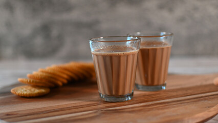 Indian Tea or Indian Chai served in a traditional tea glass with biscuits 