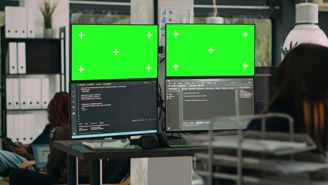 Database developer analyzing greenscreen display on multiple screens, working with server code on monitors. System engineer using isolated copyspace chromakey with mockup template in office.
