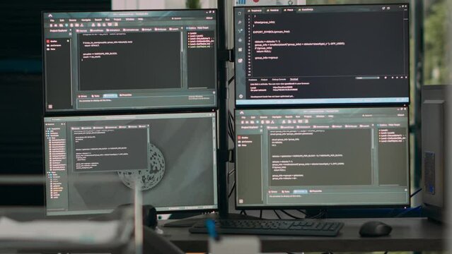 Multiple screens showing programming code in empty software it agency desk, parsing database algorithms and html text. Artificial intelligence network servers cloud computing in coding room.