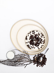 Chocolate chip cookies and black coffee grains on a dish on a white background, composition on the contrast of elements