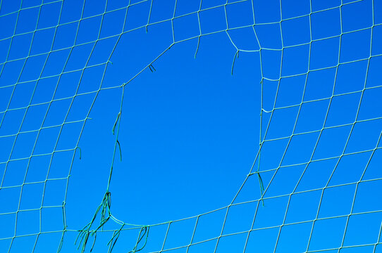 Close-up of Hole in Net against Blue Sky