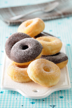 Close-up of Sugar Coated and Chocolate Dipped Donuts on Cutting Board on Blue Background